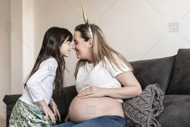 Pregnant mother playing with her daughter at sofa