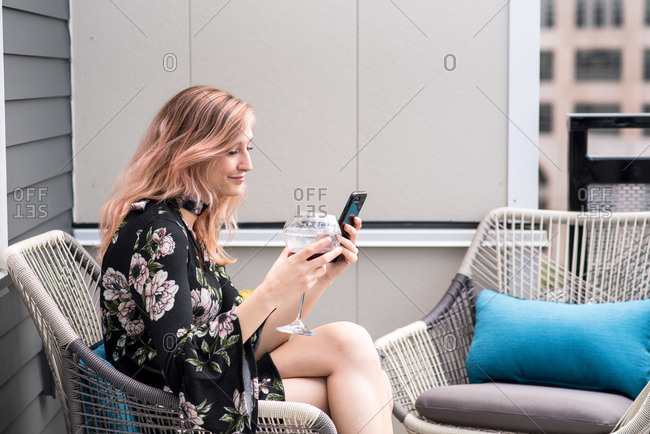 Woman texting and drinking wine while sitting outside on patio