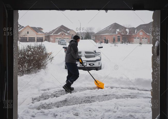Man and child shoveling snow off of a driveway on a snowy day.
