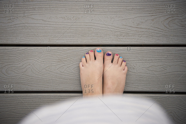 Low section of girl with colorful nail polish standing on boardwalk