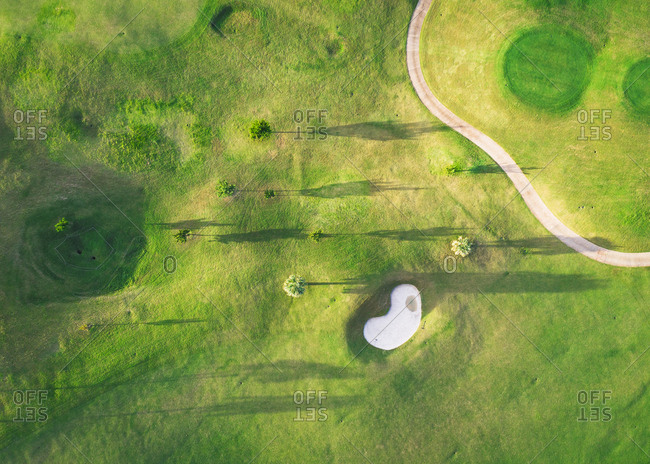 A golf course with trees and shadows from above