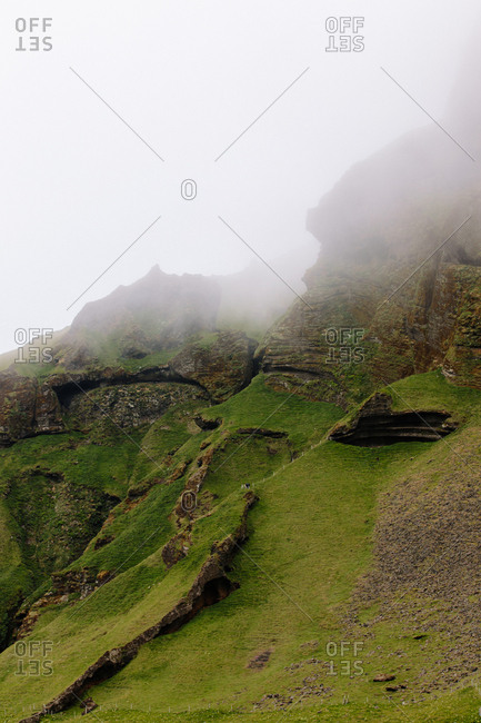 Foggy sky over green hillside in Vestmannaeyjar, Iceland