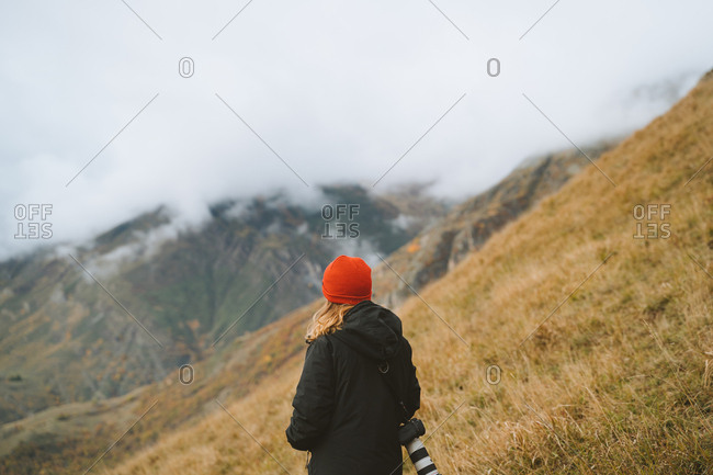 Girl wearing a red beanie taking photos on a cloudy day up in the Pyrenees mountains