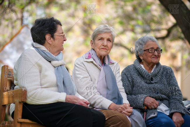 Happy old women sitting on bench in park smiling happy life long friends enjoying retirement together
