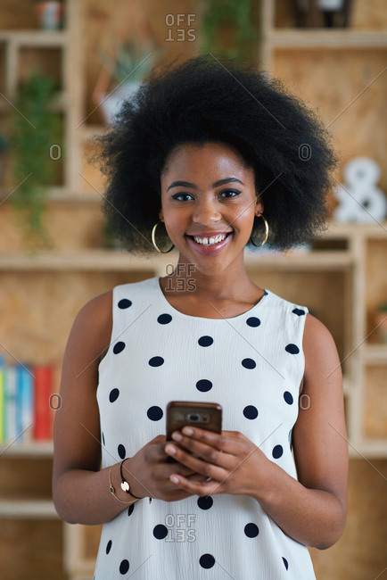 Portrait successful african american business woman smiling using smartphone in office