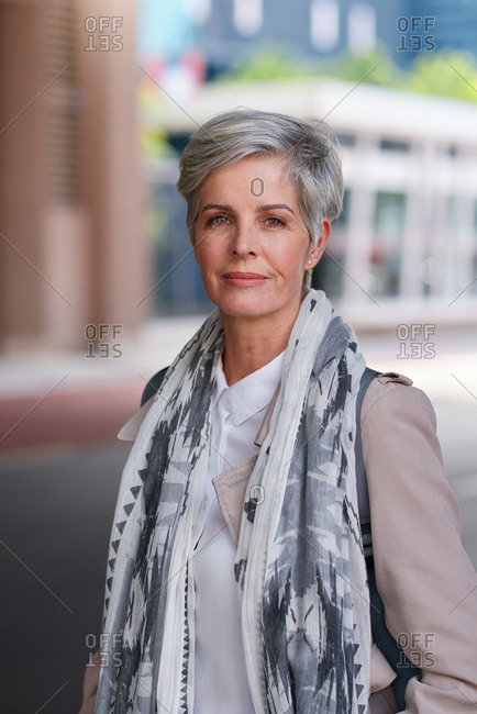 Portrait mature business woman smiling confident successful female in urban city wearing scarf success testimonial