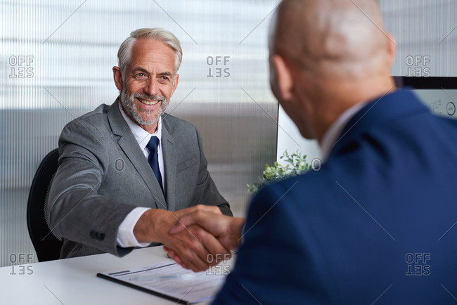 Senior businessman shaking hands with client in office meeting after successful partnership deal for startup company