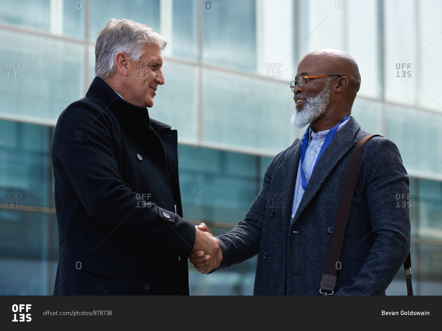Mature businessmen shaking hands in city with businessman greeting african american client with handshake