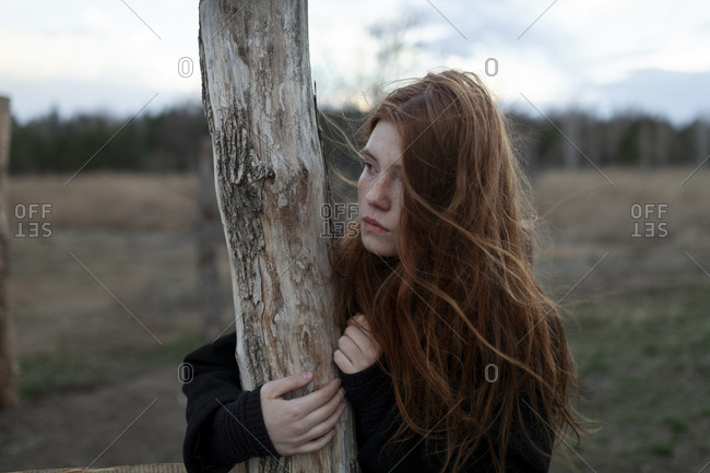 Windswept teenage girl by tree trunk