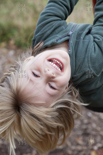 Four-year-old boy hangs headlong on a swing