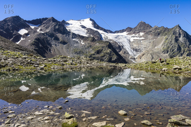 Austria, tyrol, the stubai alps, neustift, mirroring of the wilde freigers in a small lake with passing hikers