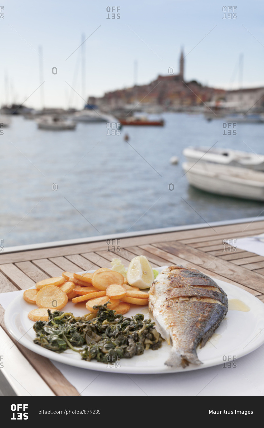 Plate with fish, potatoes and spinach in a restaurant in the harbor of rovinj, istria, croatia