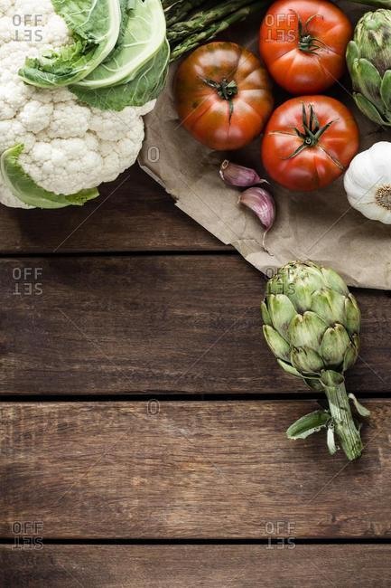 Cauliflower, artichokes, asparagus, garlic and tomatoes on a wooden table