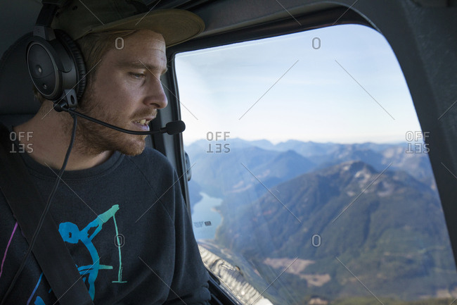 Man looking down at view from widow seat in helicopter, B.C. Canada.