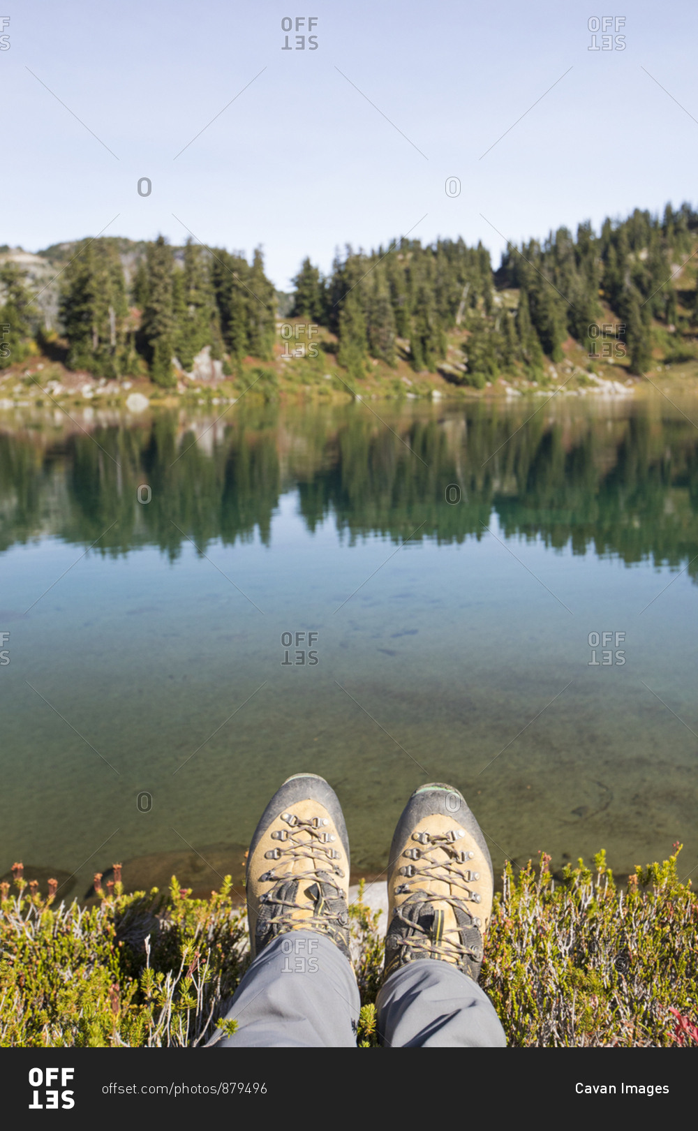 Hiking boots in front of tranquil alpine tarn, B.C., Canada.