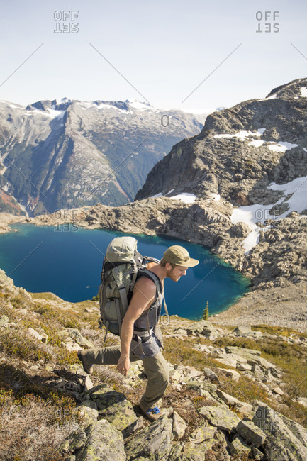 Backpacker hiking above alpine tarn, British Columbia, Canada.