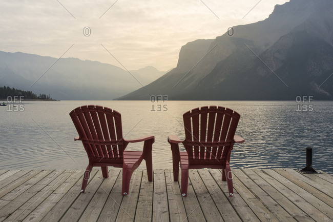 Chairs on jetty over Lake Minnewanka against mountains at Banff National Park