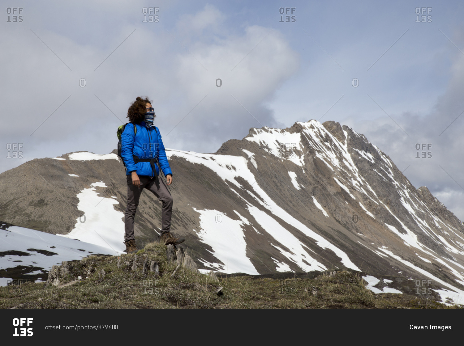 Full length of hiker with scarf covering mouth looking at view against mountains