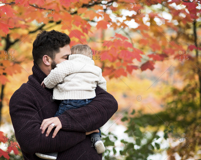 Loving father embracing son while carrying him at park during autumn