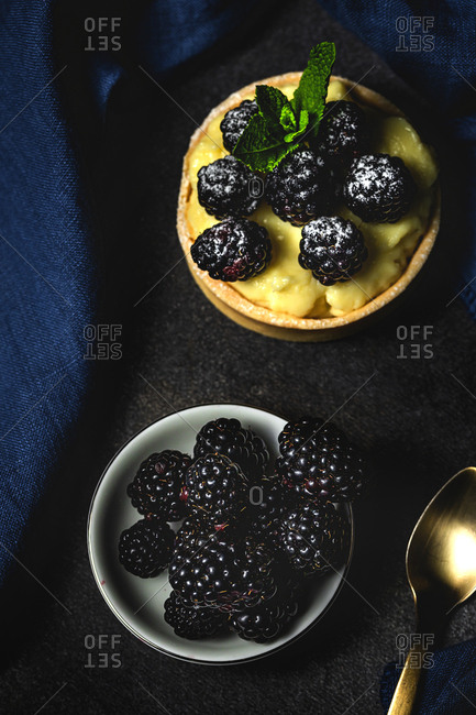 Homemade small cake with blackberry and delicious cream of vanilla and mint on dark background