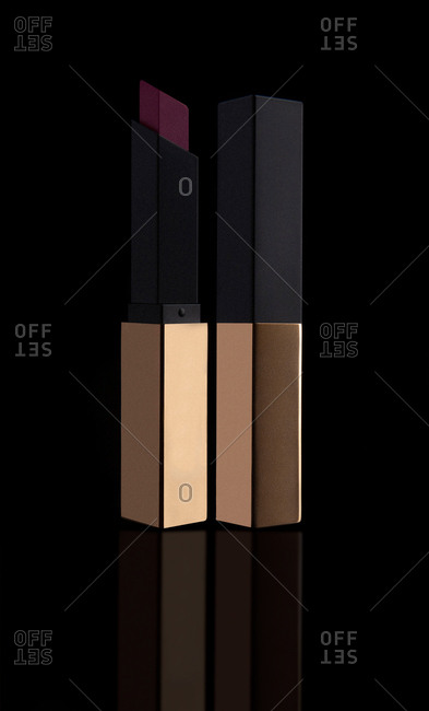 Purple foursquare open lipstick with golden cap and arranged on black background