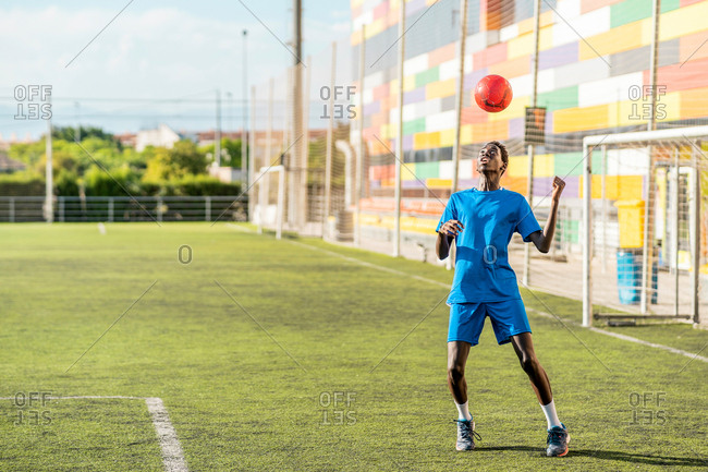 Skinny black teenager jugging football ball on head