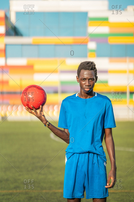 Black teenager with football ball against sky