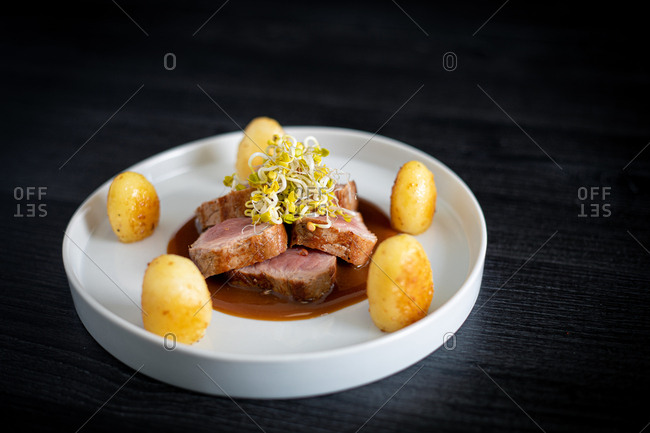 From above delicious Duroc sirloin with orange ginger soy and potatoes in white plate on black background