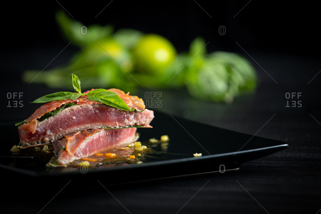 Fragrant juicy Bluefin tuna with basil ham and chicken demiglace on black plate