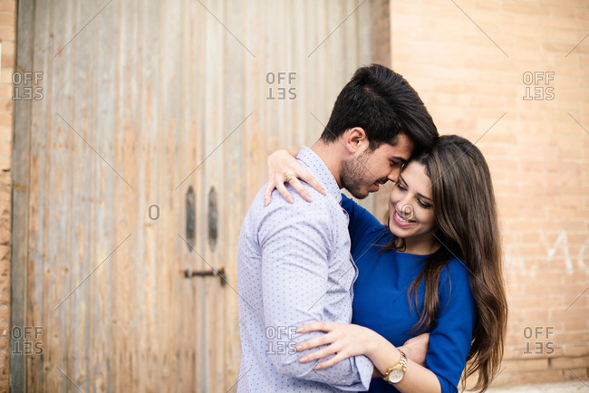 Side view of loving man and woman in elegant clothes kissing on background with columns