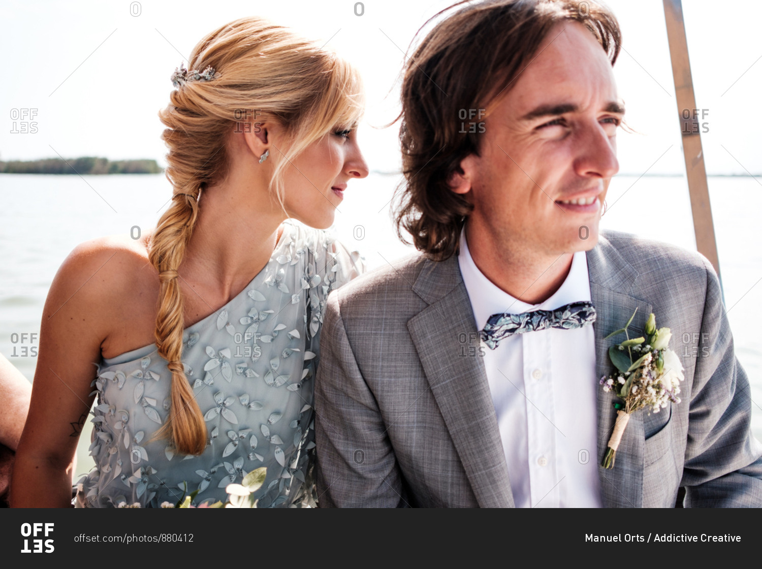 Satisfied married lovers in wedding clothing relaxing on boat with sea on background