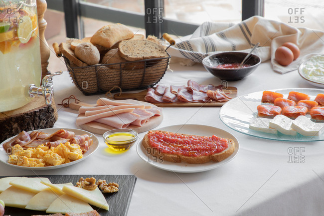 From above of tasty sandwich with red sauce and bacon serving with sauce beverage and bakery for breakfast on wooden table