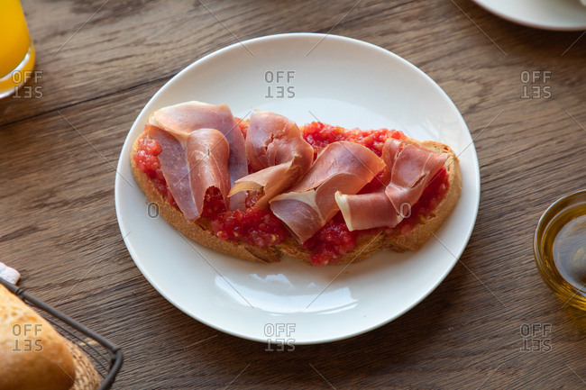 From above of tasty Spanish toast with tomato and bacon for breakfast on wooden table