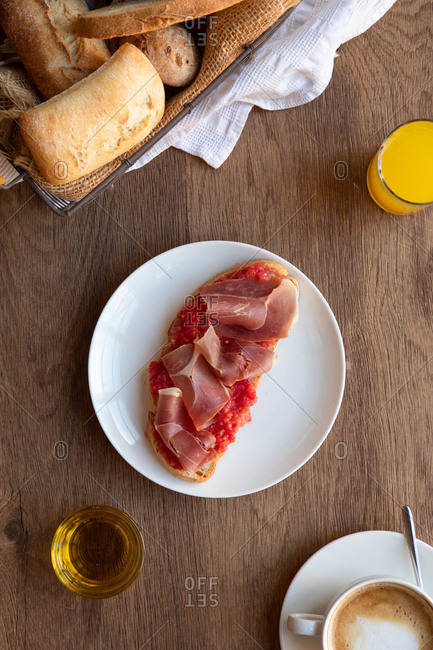 From above of tasty Spanish toast with tomato and bacon for breakfast on wooden table