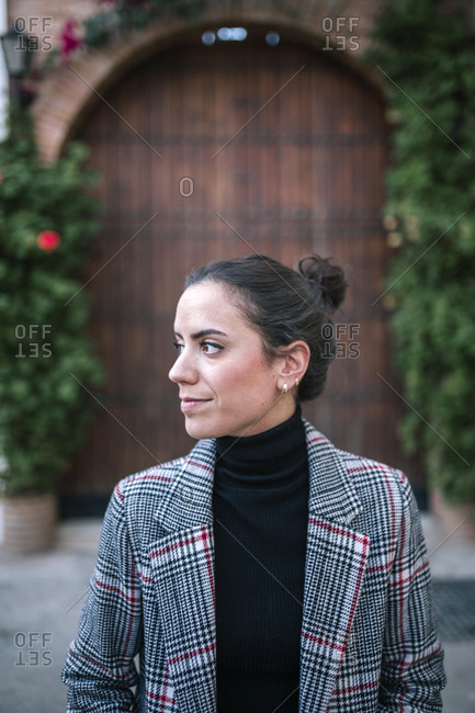 Young woman with plaid coat walking in the city