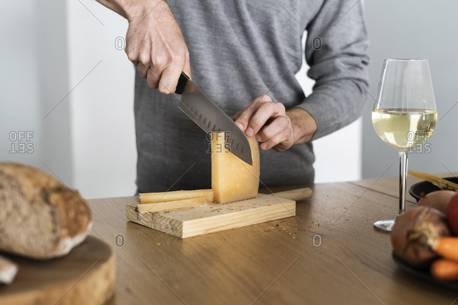 Close-up of man cutting cheese on kitchen counter