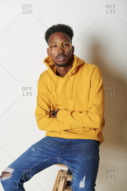 Young man wearing yellow hoodie sweater and glasses