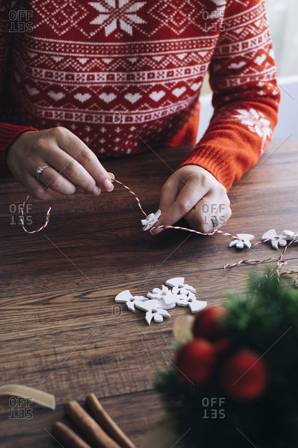 Woman making Christmas garland of a white wooden angels