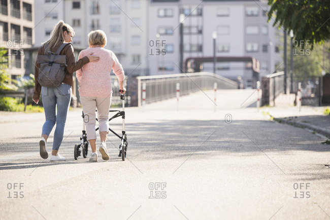 Granddaughter assisting her grandmother walking with wheeled walker