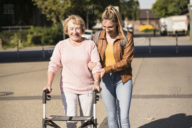 Granddaughter assisting her grandmother walking with wheeled walker