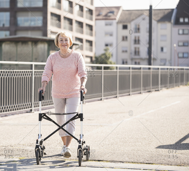 Senior woman with wheeled walker on footbridge