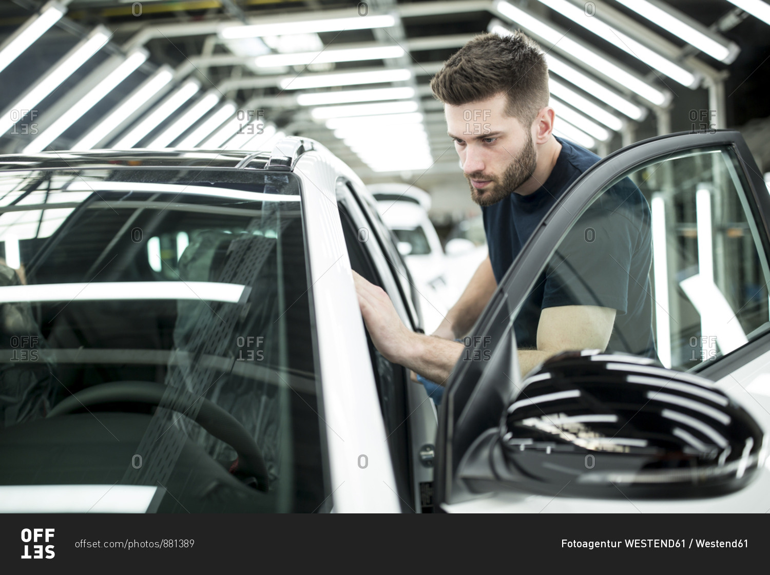 Man working in modern car factory wiping finished car