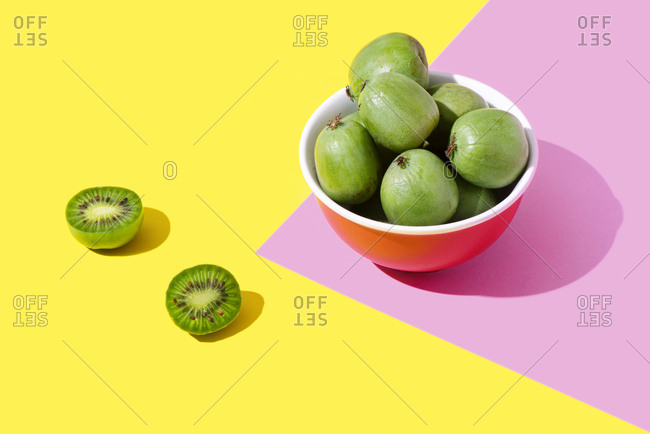 Kiwi berries in a pink bowl on a yellow and pink background