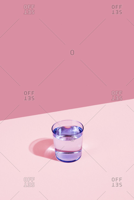 Glass of water against a pink background