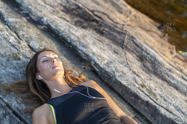 Woman lying on rocks with eyes closed