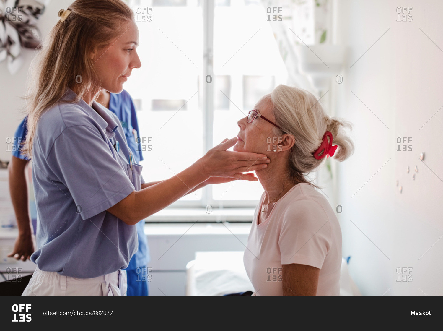 Mature female doctor examining patient\'s throat in medical examination room