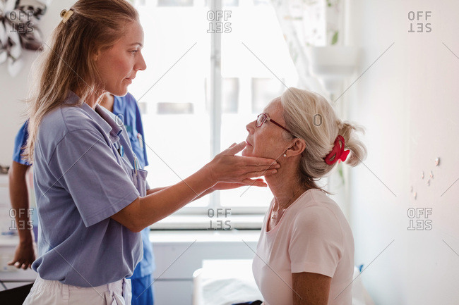 Mature female doctor examining patient's throat in medical examination room
