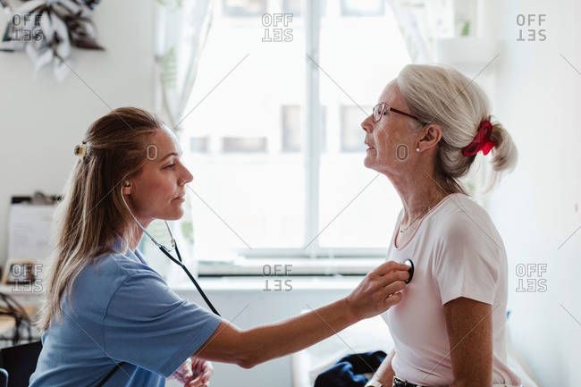 Side view of female doctor examining senior patient in medical clinic