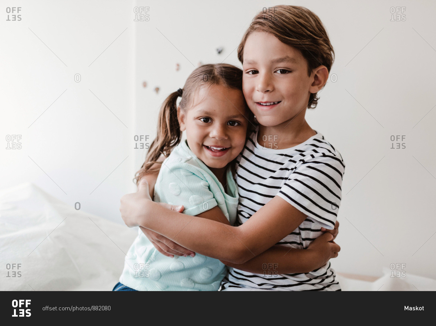 Portrait of smiling brother and sister embracing while sitting in medical examination room