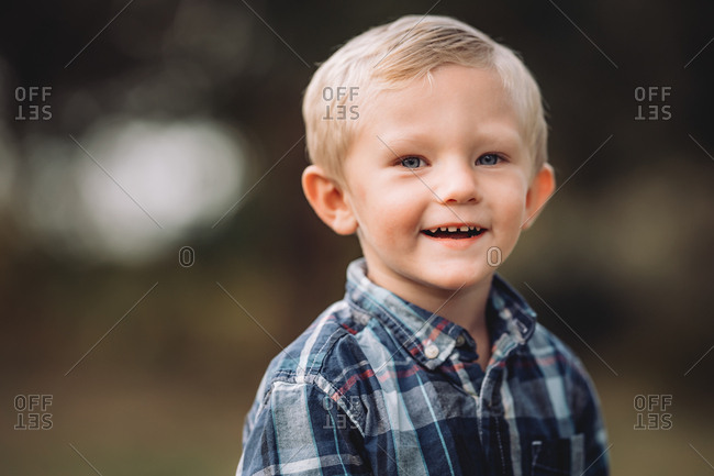 Happy blonde boy wearing a blue plaid shirt